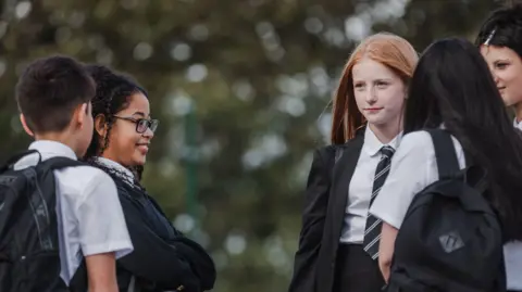Teenage students chatting at break time in a secondary school playground.