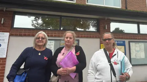 Lesley Webb, Lindsey Collins and Nicola Smith outside the Broxtowe Borough Council headquarters in Beeston wearing poppies and holding notebooks.