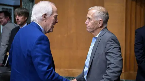 AFP via Getty Images US Senator John Cornyn, Republican from Texas, speaks with Senator Thom Tillis, Republican from North Carolina, during a Senate Finance Committee hearing on Capitol Hill in Washington, DC,