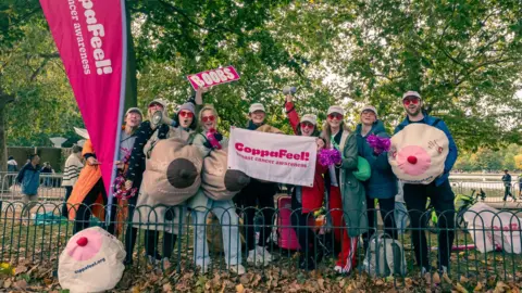 CoppaFeel CoppaFeel charity fundraisers cheering with signs at the 2024 Royal Parks Half Marathon 