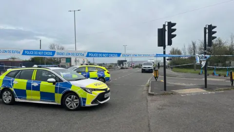 Two police cars and a police cordon on the intersection of a main road in Filton, north Bristol.