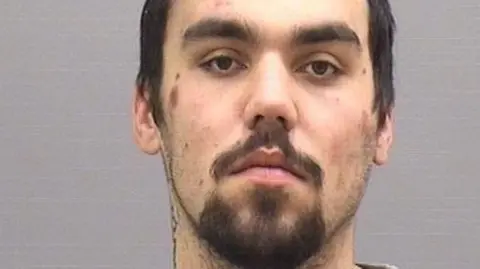 Custody photo of Jake Saunders who has short dark hair and a goatee beard