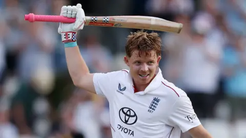 England batter Ollie Pope raises his bat to celebrate hitting a century