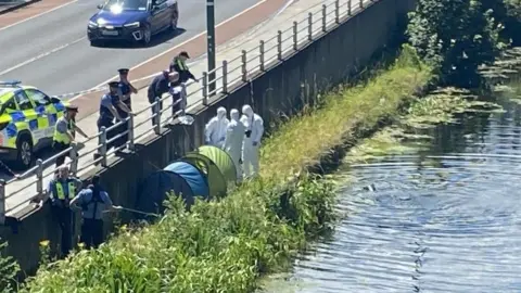 RTÉ Gardaí and emergency services pictured beside the canal. Two tents and forensic officers are on the bank of the canal.