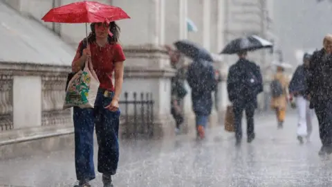 EPA/Shutterstock A person walks with an umbrella during heavy rain.