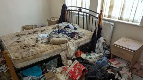 RSPCA An unmade bed with a mattress covered in animal faeces and large amounts of household waste covering the floor