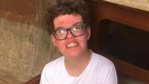 Family photo of Fraser. He is wearing a white T-shirt and glasses