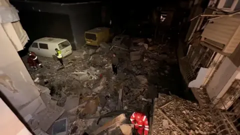 Emergency services work at a site damaged during a Russian drone attack in Odesa, Ukraine, in this screengrab from a video released by mayor Hennadii Trukhanov on Telegram.