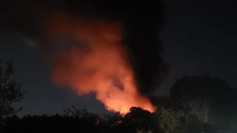 A fire at night with a large cloud of smoke billowing in the air.