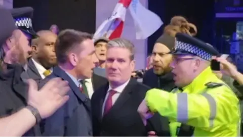 Sir Keir Starmer surrounded by police and protesters