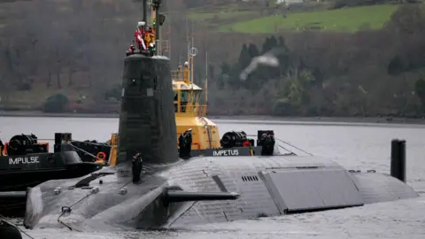A Vanguard class submarine in dock at Faslane. Three submariners in uniform can be seen on the deck