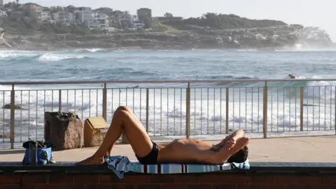 EPA A man sunbakes at a Sydney beach