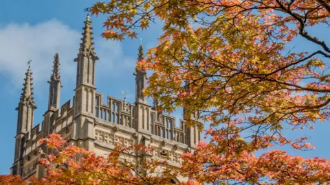 WEDNESDAY - An Oxford tower against a blue sky with the golden leaves of a tree