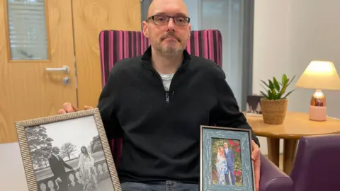 Mark Ansell / BBC David Crozier with wedding photos of him and his wife Tracey Ling