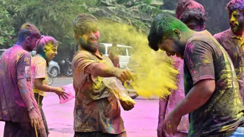 Getty Images Revellers smear coloured powder on one another during Holi festival celebrations, at Girgoan, on March 14, 2025 in Mumbai, India.