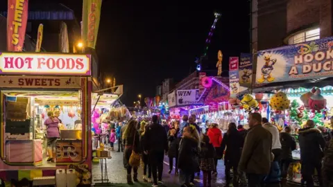 Crowds at Ilkeston Charter Fair with stalls either side of the street