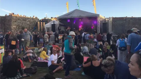 BBC Small crowd sitting in field area
