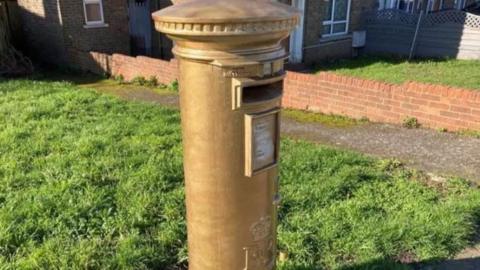 A gold spray painted post box in Dartford 