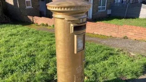 Phil Harrison/BBC A gold spray painted post box in Dartford 