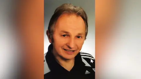 Headshot of a man wearing an Adidas polo shirt smiling at the camera