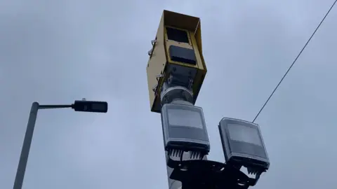 A yellow-coloured metal camera box with two plastic sensor below it