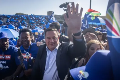 Getty Images acenando para a multidão, o líder da Aliança Democrática (DA), John Steenhuisen, chega para falar durante um comício realizado no Stadium Willowmoore, Benoni, em 26 de maio de 2024 em Joanesburgo, África do Sul