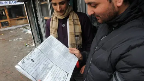 Men reading a newspaper in Srinagar