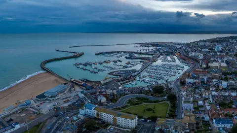 Ariel view of Port of Ramsgate. There are clouds in the sky and many boats in the distance. 