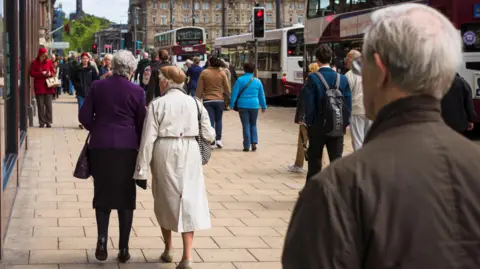 Getty Images People walking along Princes Street in Edinburgh, including some with white hair