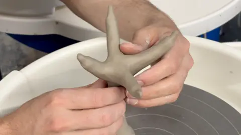 Simon Balch A potter moulds and shapes clay into the shape of a chicken's foot. 