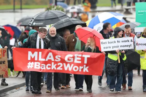 PA Media People march at Stormont to mark 1,000 days since the Northern Ireland Assembly collapsed