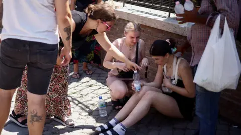 Reuters A tourist from the UK receives help near the Colosseum after fainting during the heatwave in Rome