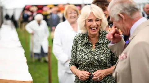 PA Media Kings Charles III and Queen Camilla laugh as they view a display during the Sandringham Flower Show at Sandringham House in Norfolk