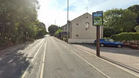 Google The A58, which runs past the Valley Inn pub. A blue car is parked next to the pub.