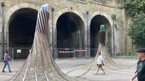 BBC The Fibres sculpture in Bradford Forster Square with fenced-off archways in the background