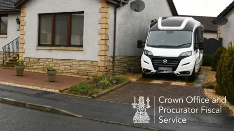 A white motorhome is parked in the driveway of a modern bungalow home 