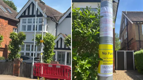 Katy Lewis/BBC A suburban street view showing a pair of large detached houses, with a temporary red safety barrier placed around a lamppost in front. A closer panel highlights a notice attached to the lamppost announcing upcoming street‑lighting maintenance and temporary “No Parking” restrictions on specific dates.