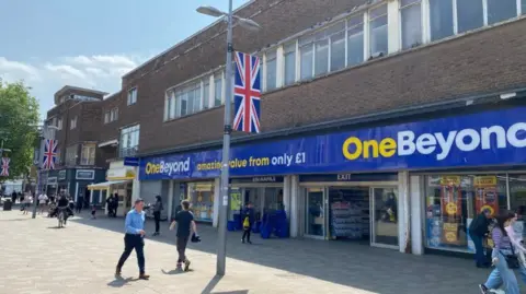 Hull City Council Exterior shot of a two-storey post-war building. There is a row of windows on the first floor and the ground floor space is being used as a retail space. There is a large blue and yellow sign which reads: "One Beyond".