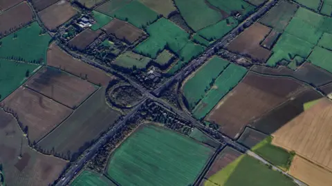 A view of M5 J10 from above showing fields around the side and the roads leading to it