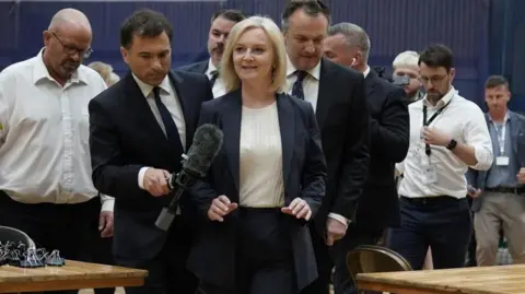 PA Media Liz Truss followed by reporters and officials