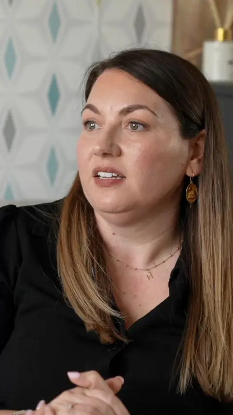 A woman looking slightly off camera with her hands together