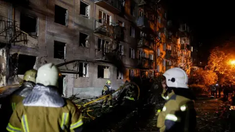Firefighters work at the site of an apartment building hit by a Russian missile strike in Kyiv