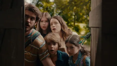 Entertainment Film Distributors A family looks in awe through an open old door