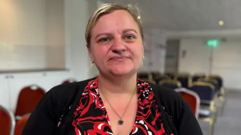 Head and shoulders of Sarah Sissons who is wearing a black, red and white top.