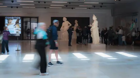 Wojtek Lubowiecki Visitors mill about the statues in the hall.