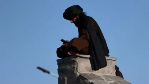 AFP via Getty Images A Taliban fighter uses his phone at Wazir Akbar Khan hilltop in Kabul on August 30, 2022