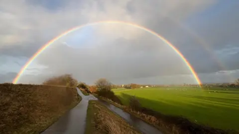 buckles A double rainbow over a small country lane.