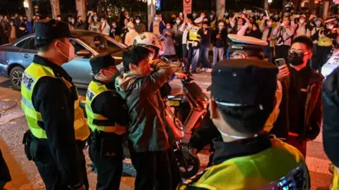 Getty Images Police officers confront a man amid crowded scenes at a road junction in Shanghai