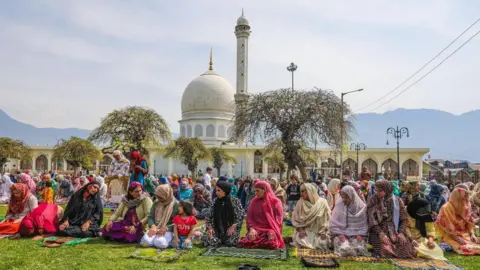 EPA Women sitting on the grass with white dome in the background in Srinagar, Indian-administered Kashmir