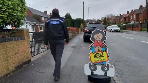 Derbyshire Police A police community support officer walks along a residential street while on a parking patrol